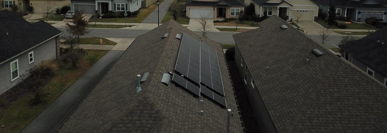 View of a roof in a neighborhood with black solar panels